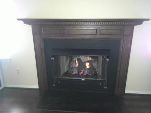 After: Zero Clearance Wood Stove Updated With Custom Mantel, Vent Free Gas Log Set, Hood And Glass Doors
